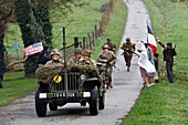 France,Eure,Sainte Colombe prés Vernon,Allied Reconstitution Group (US World War 2 and french Maquis historical reconstruction Association),reenactors in uniform of the 101st US Airborne Division progressing in a jeep Willys welcomed as liberators by villagers and FFI