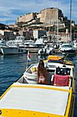 A young woman in skimpy swimwear onboard a yellow speed boat in the marina at Bonifacio. Corsica. France.
