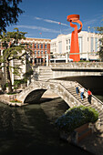 Der malerische River Walk. San Antonios Attraktion Nummer eins - eine Promenade mit Bars und Restaurants unterhalb des Straßenniveaus. Im Hintergrund ist die Fackel der Freundschaft zu sehen, San Antonio, Texas, USA
