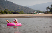 Kiki Lett schwimmt auf einem Ring im sicheren seichten Wasser einer Flussmündung im Urlaub in Indien, Palolem Beach, Goa, Indien.