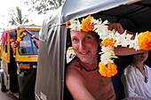 Der Bräutigam nimmt ein mit Blumengirlanden geschmücktes Rikscha-Taxi, Patnum, Goa, Indien.