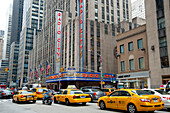 Taxis Passing By Radio City Music Hall,Famous Entertainment Venue Located In Rockefeller Center,Midtown Manhattan,New York,Usa