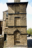 Ein Haus mit zugemauerten Fenstern als Ergebnis der Fenstersteuer in Saltaire, einem viktorianischen Modelldorf, Bradford, West Yorkshire, England