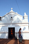 Guy passing church,Christianity is the popular religion in the ex-Portugese colony of Goa,heading to world famous Anjuna Flea Market,held on Wednesdays on Anjuna Beach,Goa State,India,Asia.