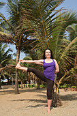 Trained yoga teacher doing yoga poses/ postures along Anjuna Beach. Goa State,India,Asia.