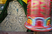 India,Spinning prayer wheel and Buddhist rock carving on the outer walls of Pemayangtse Monastery,West Sikkim