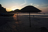 Indien,Sonnenschirme bei Sonnenuntergang am Strand von Palolem, Goa