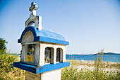 Greece,Halkidiki,Shrine along coast road with Meditarrenean sea visible in distance,Ouranoupoli