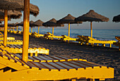 Spain,Yellow beach chairs and straw sun umbrellas,Malaga