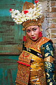 Indonesia,Bali,Legong dancer next to a traditional Balanese gate in Ubud. Gates such as these are thought to be a barrier to evil spirits entering home,Ubud