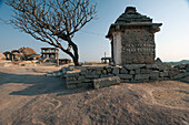 Religiöses und historisches Bauwerk neben einem blattlosen Baum,Hampi,Karnataka,Indien