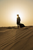 Barefoot Man With Suitcase On Sand Dune At Dusk,Dubai,United Arab Emirates