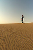 Man In Smart Suit Making Phone Call On Top Of Sand Dune At Dusk,Dubai,United Arab Emirates