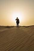 Man In Smart Suit Making Phone Call On Top Of Sand Dune At Dusk,Dubai,United Arab Emirates