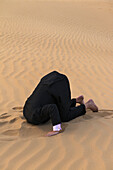 Man In Smart Suit With Head Buried In The Sand,Dubai,United Arab Emirates