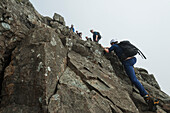 Wanderer kraxeln auf steilem Fels nahe dem Gipfel des Sgurr Alasdair in den Black Cuillin, Isle Of Skye, Schottland