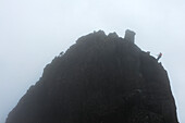 Menschen, die den unzugänglichen Gipfel auf der linken Seite erklimmen, während andere sich auf der rechten Seite bei nebligen Bedingungen abseilen, Sgurr Dearg, Isle Of Skye, Schottland