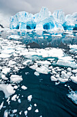 Sea ice floats in Neko Harbor in the Southern Ocean,with tunnels formed in the blue ice in the background,Antarctica