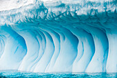 Gebogene blaue Eisformationen auf einem Eisberg in der Cierva-Bucht im Südlichen Ozean, Antarktis