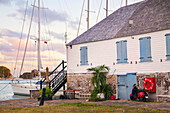 Segelboot am Ufer des historischen Nelsons Dockyard mit einem alten Haus und einer Festung, die in ein Restaurant und einen Souvenirladen umgewandelt wurden, auf der Insel Antigua, English Harbour, Antigua, Karibik