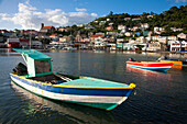 Hafenszene mit bunten Fischerbooten, die in Ufernähe vertäut sind, und der Hafenstadt St. Georges im Hintergrund an einem sonnigen Tag, St. Georges, Grenada, Karibik