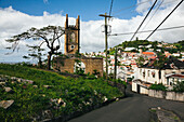 Straße durch die Hafenstadt St. Georges mit der St. Andrew's Presbyterian Church (die 2004 durch den Hurrikan Ivan schwer beschädigt wurde) und den bunten Häusern am Berghang auf der Insel Grenada, St. Georges, Grenada, Karibik