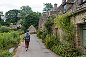 Frau geht einen gepflasterten Weg neben Häusern in Großbritannien entlang, Vereinigtes Königreich