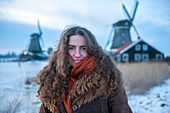Junge Frau posiert in Zaanse Schans, einem historischen Windmühlengebiet in den Niederlanden, Amsterdam, Niederlande