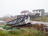 Verfallenes Skiff am Ufer sitzt auf einem Haufen Bauschutt, Battle Harbour, Neufundland und Labrador, Kanada