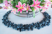 Polished black stones ring a bouquet of pink lilies,Republic of the Maldives
