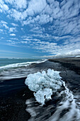 Kleiner Eisberg vom Vatnajokull am Ufer eines schwarzen Sandstrandes, Island