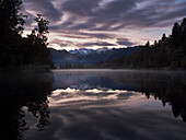 Sonnenaufgang am Lake Matheson, mit Mount Tasman und Mount Cook in der Ferne, Fox Glacier, Südinsel, Neuseeland