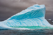 Eisberg schwimmt gegen stürmischen Himmel,Antarktis
