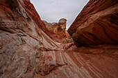 Blick durch streifige Gesteinsmuster und hügelige Felsformationen unter bewölktem Himmel, die Teil der fremdartigen Landschaft mit erstaunlichen Linien, Konturen und Formen in dem wundersamen Gebiet namens White Pocket in Arizona, Arizona, Vereinigte Staaten von Amerika sind
