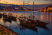Boote mit Weinfässern im Hafen von Porto in der Abenddämmerung, Porto, Portugal