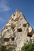Nahaufnahme von in spitze Felsformationen gehauenen Höhlenwohnungen vor einem strahlend blauen Himmel in der Nähe der Stadt Goreme im Pigeon Valley, Region Kappadokien, Provinz Nevsehir, Türkei