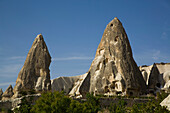 Cave Houses in rock formation peaks against a bright blue sky near the town of Goreme in Pigeon Valley,Cappadocia Region,Nevsehir Province,Turkey