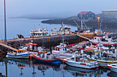 Ein spätabendlicher, nebliger Blick auf den Hafen und die Fischerdocks in Djupivogur, Ostisland, wo es spät in der Nacht noch hell ist, wenn sich die Sommersonnenwende nähert, Djupivogur, Island