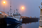 Ein Fischerboot liegt im späten Nachtnebel an den Docks des Dorfes Djupivogur, Ostisland, während der Sommersonnenwende still, Djupivogur, Island