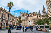 Segways and tourists in Plaza del Triunfo,with Seville Cathedral on the right and General Archive of the Indies on the left,Seville,Spain