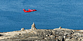Small red plane flies over the rugged,rock coastline of Greenland,Nuuk,Sermersooq,Greenland