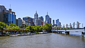 Skyline der Gebäude in Melbourne vom Ufer und der Sandridge-Brücke über den Yarra River aus gesehen, Melbourne, Victoria, Australien