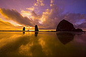 Silhouetted Haystack Rock und andere Sea Stacks im pazifischen Ozean in Cannon Beach bei Sonnenuntergang, Oregon Küste, Cannon Beach, Oregon, Vereinigte Staaten von Amerika