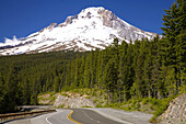 Schnee bedeckt einen majestätischen Mount Hood mit einem dichten Wald, der den Highway und den Berghang säumt, Mount Hood National Forest, Oregon, Vereinigte Staaten von Amerika