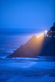 Lighthouse lamp illuminating the coastline through the fog at dawn,Oregon coast,Oregon,United States of America