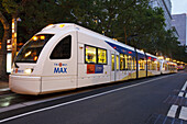 Max Train, Portlands Stadtbahn, die in der Abenddämmerung auf der Straße fährt, Portland, Oregon, Vereinigte Staaten von Amerika