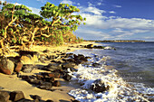 Brandung plätschert auf einen Strand mit Felsen und Blick auf die Küstenlinie in der Ferne, Kauai, Hawaii, Vereinigte Staaten von Amerika