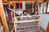 Eine Frau webt an einem Webstuhl in Peguche, einem Weberdorf in der Nähe von Otavalo, Ecuador