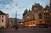 In der Abenddämmerung auf dem Prager Platz der Republik gehen Fußgänger an einem Theater vorbei,Prag,Tschechische Republik
