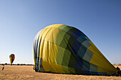 Several people deflate hot air balloons in an open field.,Winters,California